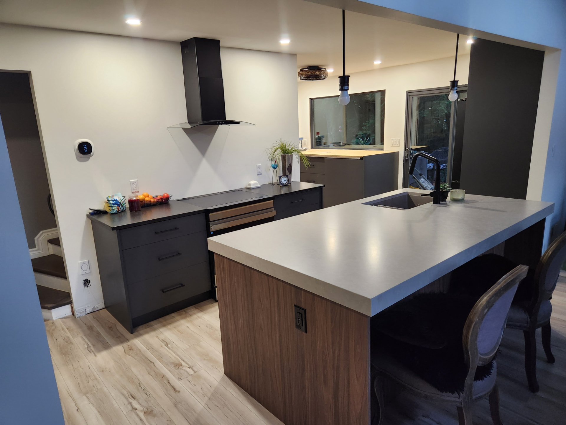 Finished kitchen with walnut island, concrete-look quartz counter and matte black fixtures