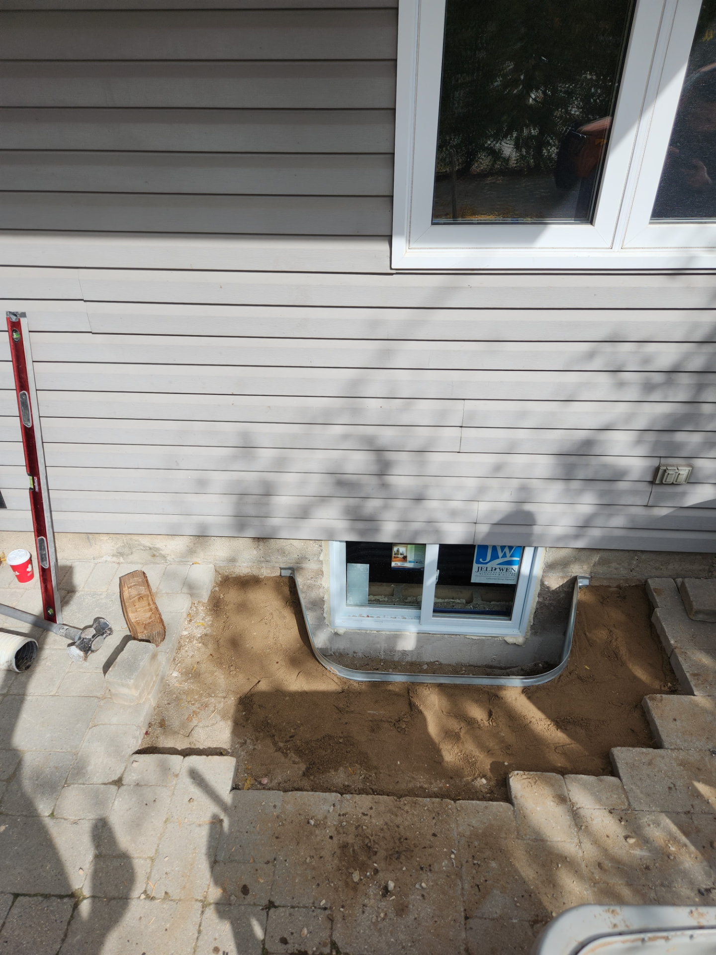 Egress window and well installed with framing and waterproofing in progress