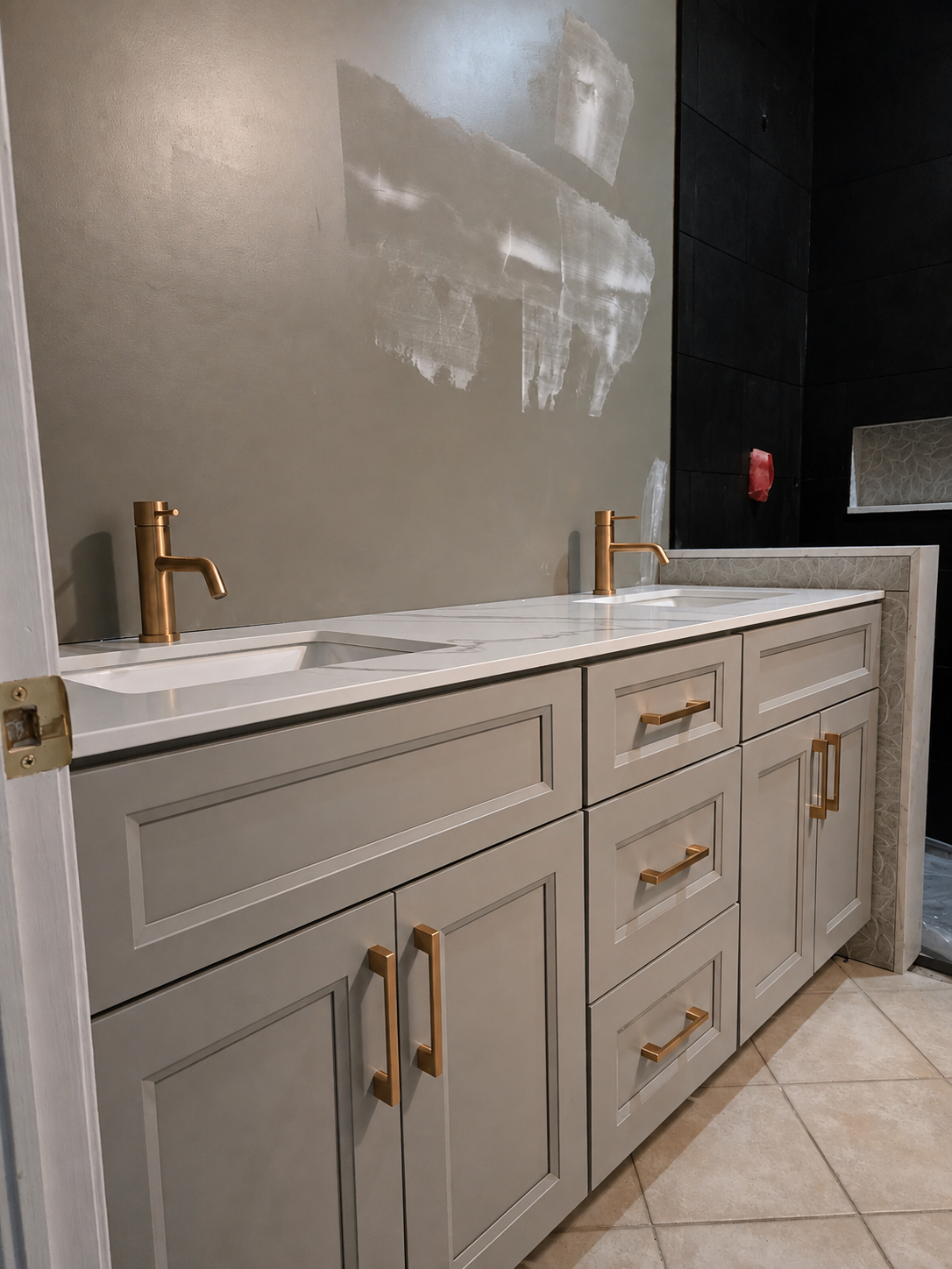 Double greige shaker vanity with quartz waterfall top and brushed gold faucets and handles