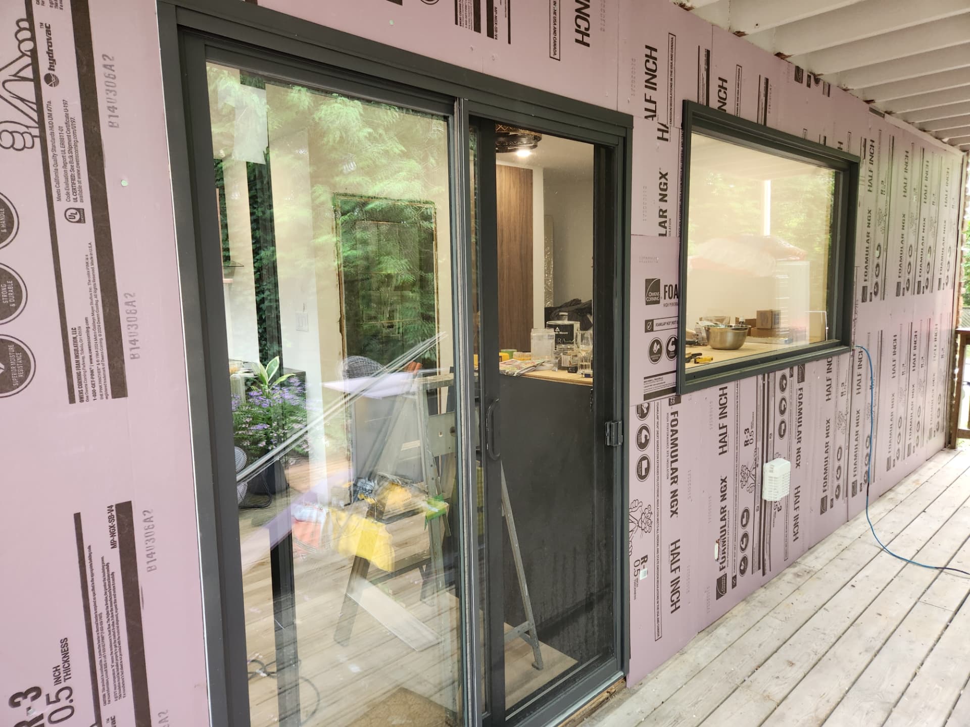Rigid foam insulation taped over the sheathing around the new door and window openings