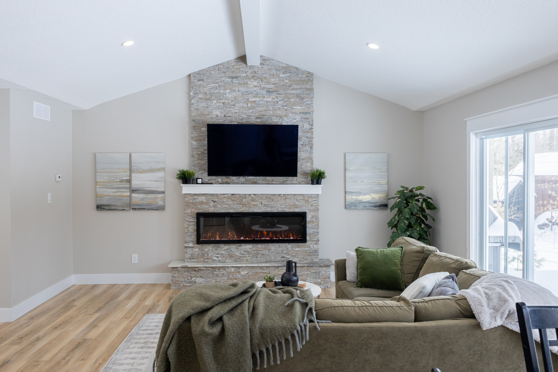 Living room with floor-to-ceiling stacked stone fireplace, mounted TV, white mantel and cozy seating area