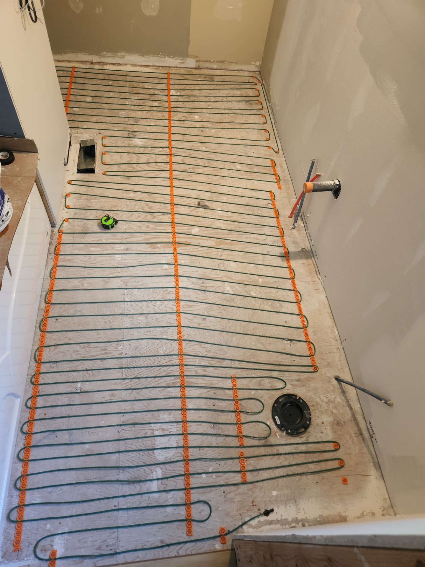 In-floor heating cable laid over the bathroom subfloor before tiling