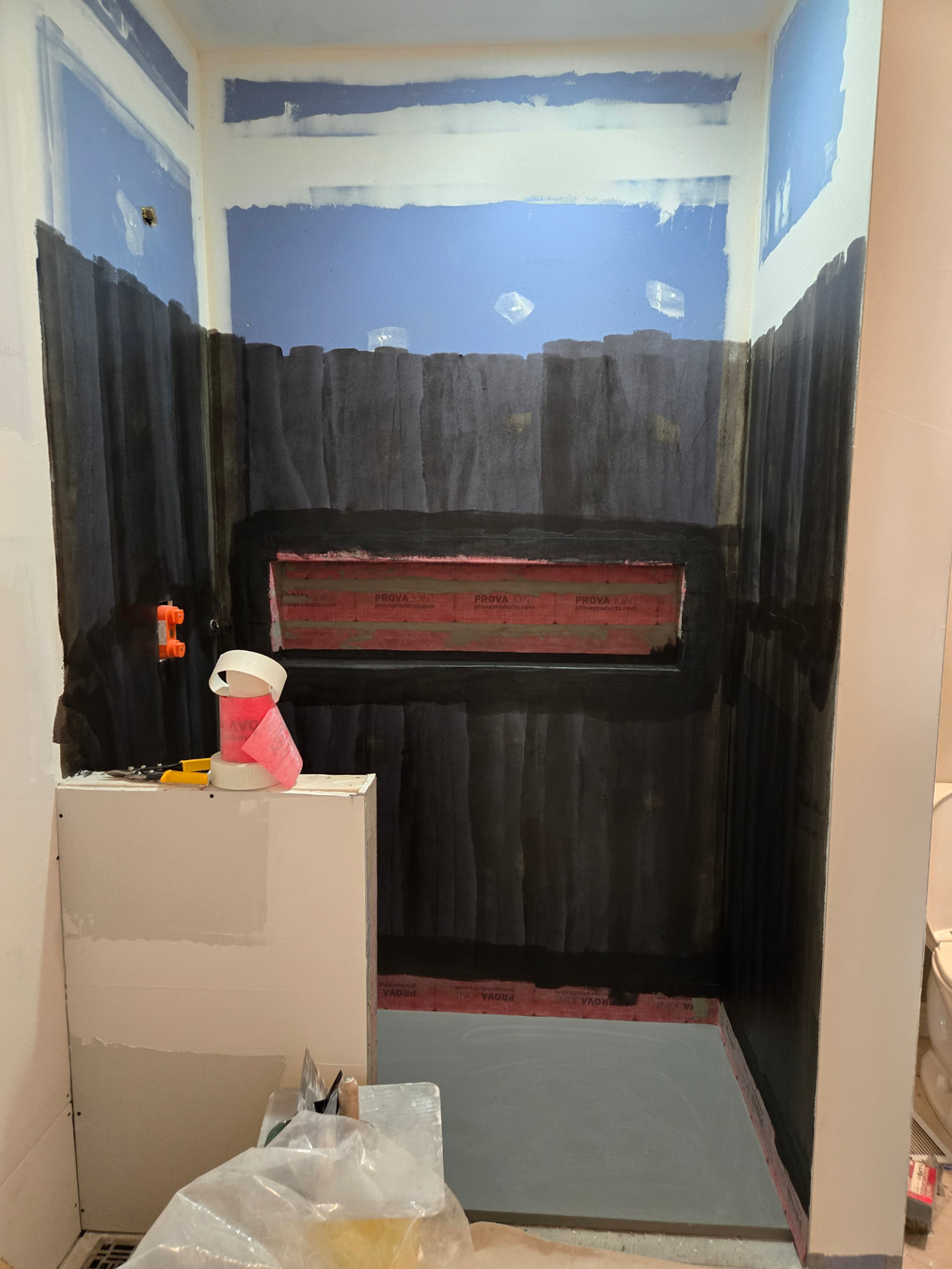 Shower walls, curb and niche coated in liquid waterproofing membrane with banded seams