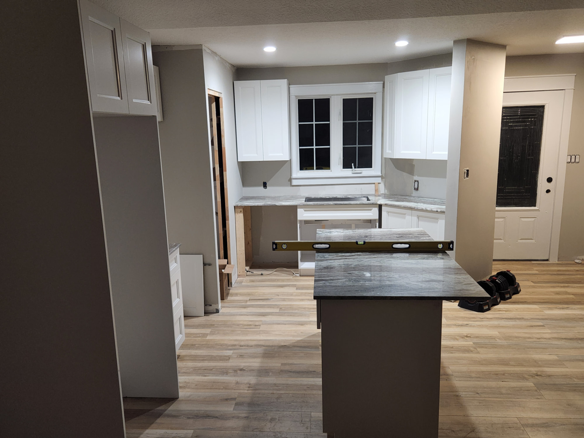 White shaker cabinets and marble-look counters being levelled during the kitchen install