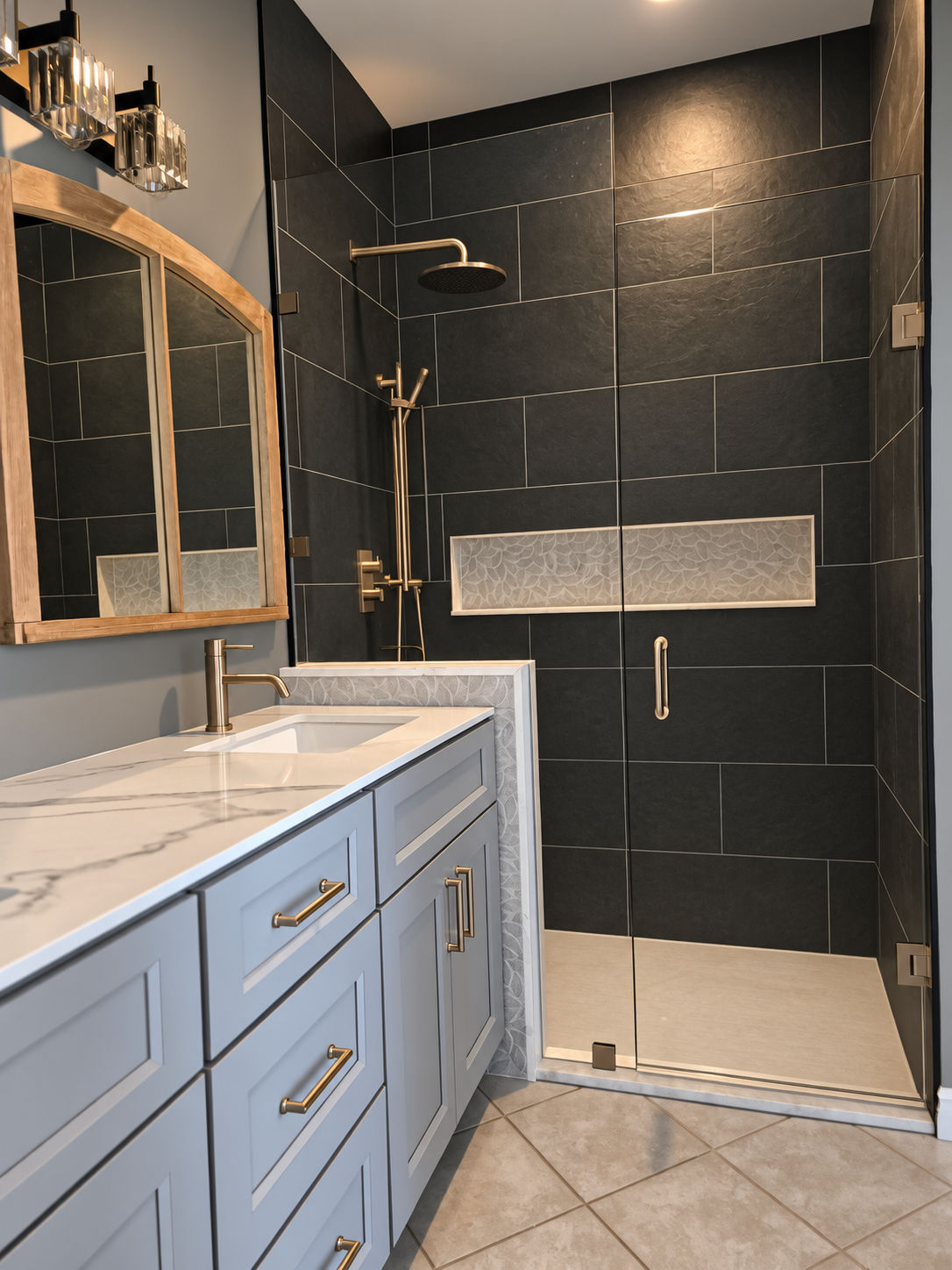 Finished bathroom with black tile walk-in shower, light grey vanity and brushed gold fixtures