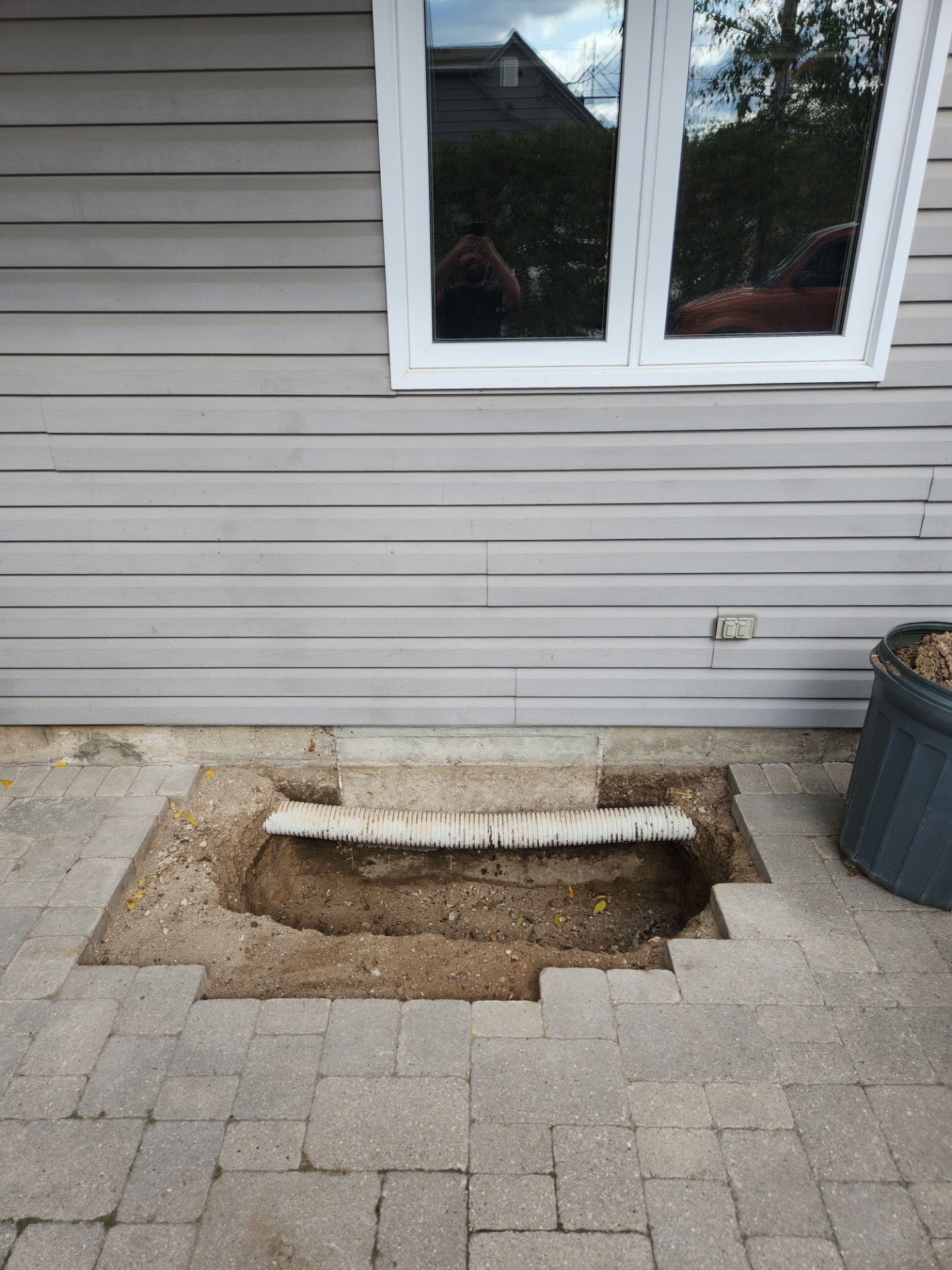 Excavated window well with soil removed and foundation cut for egress window installation