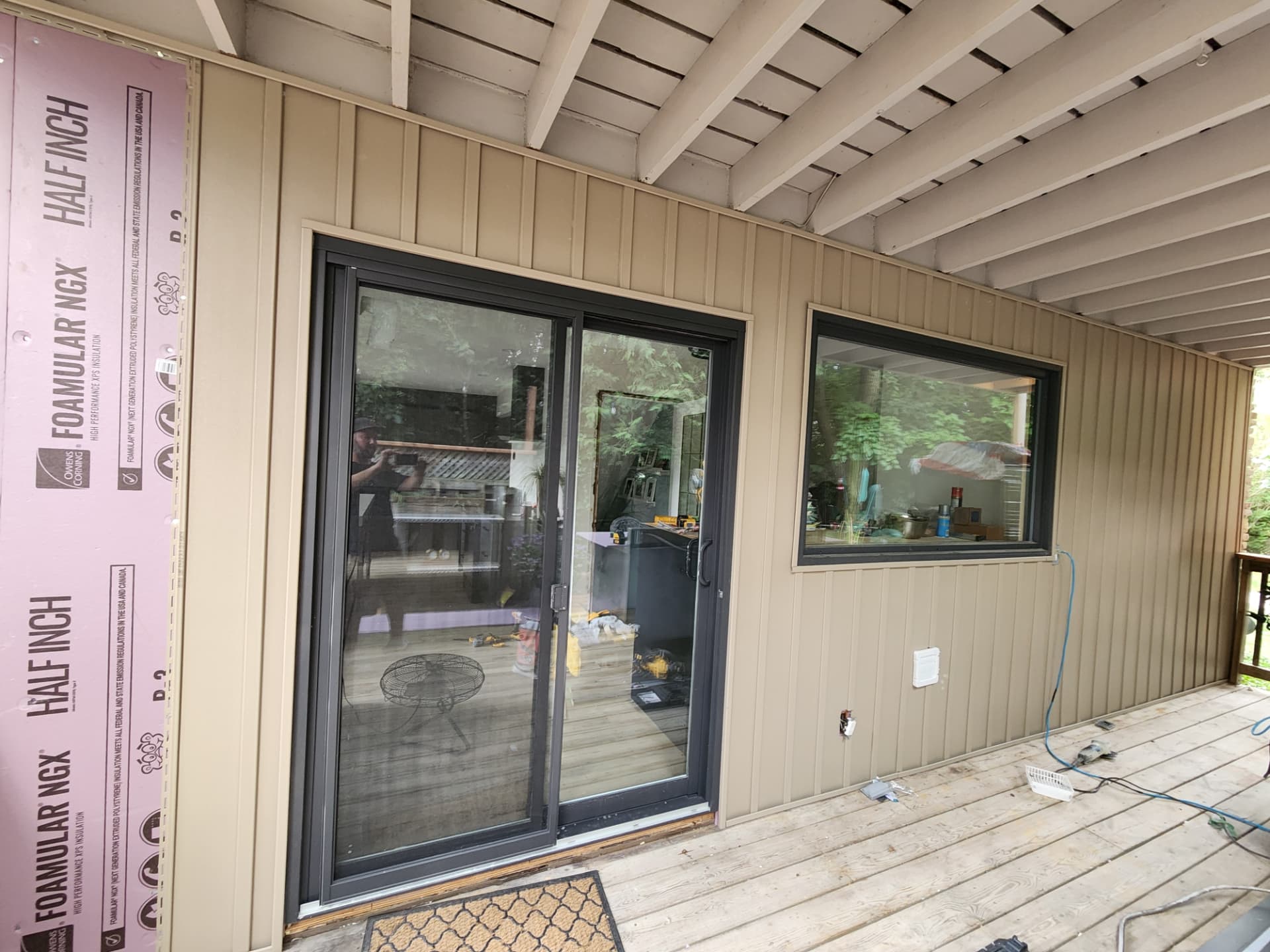 Completed wall with board and batten siding wrapping the new black patio door and window