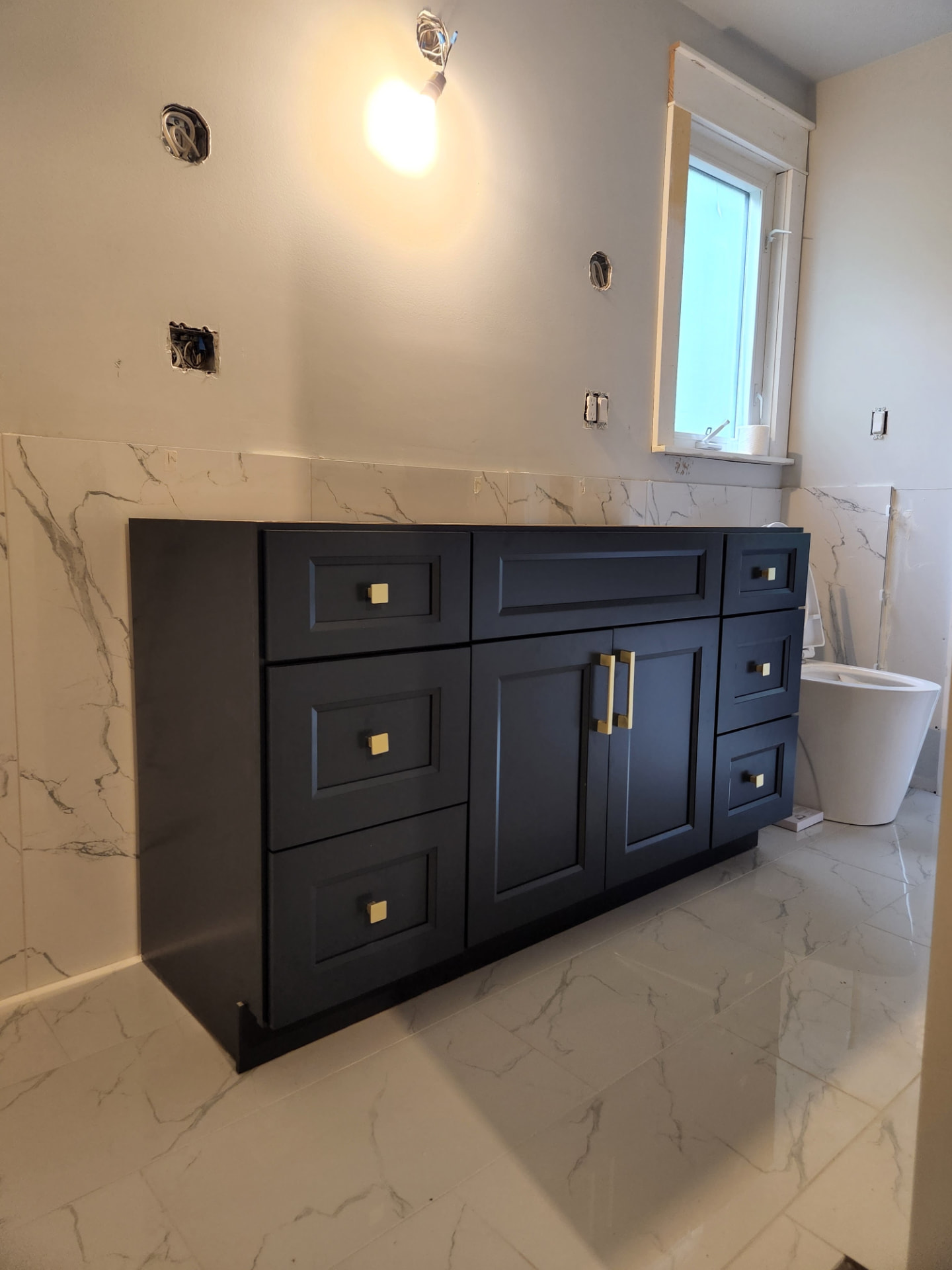 Navy shaker vanity set in place against the marble tile surround
