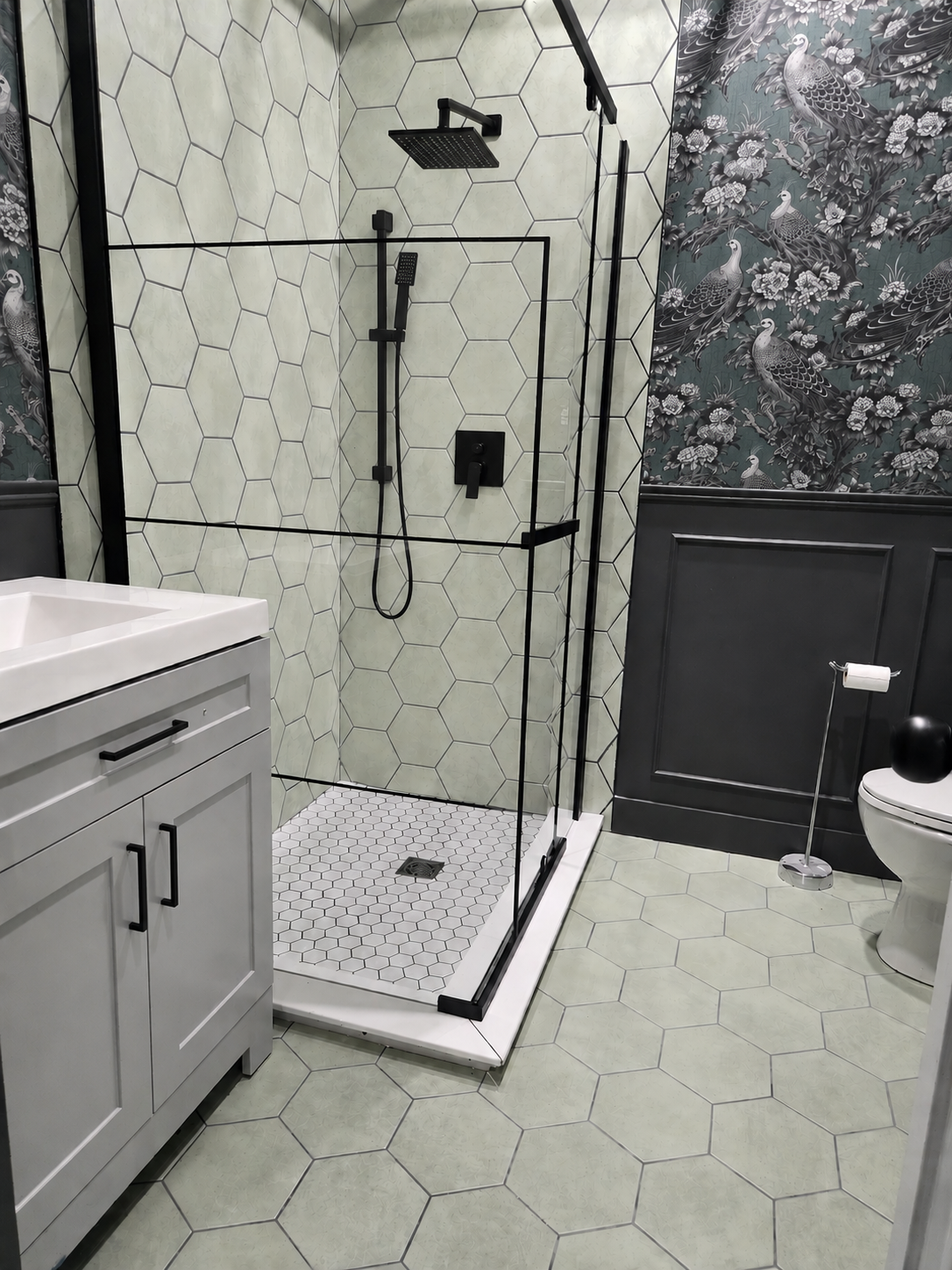 Finished bathroom with matte black fixtures, glass shower, dark wainscoting and peacock wallpaper