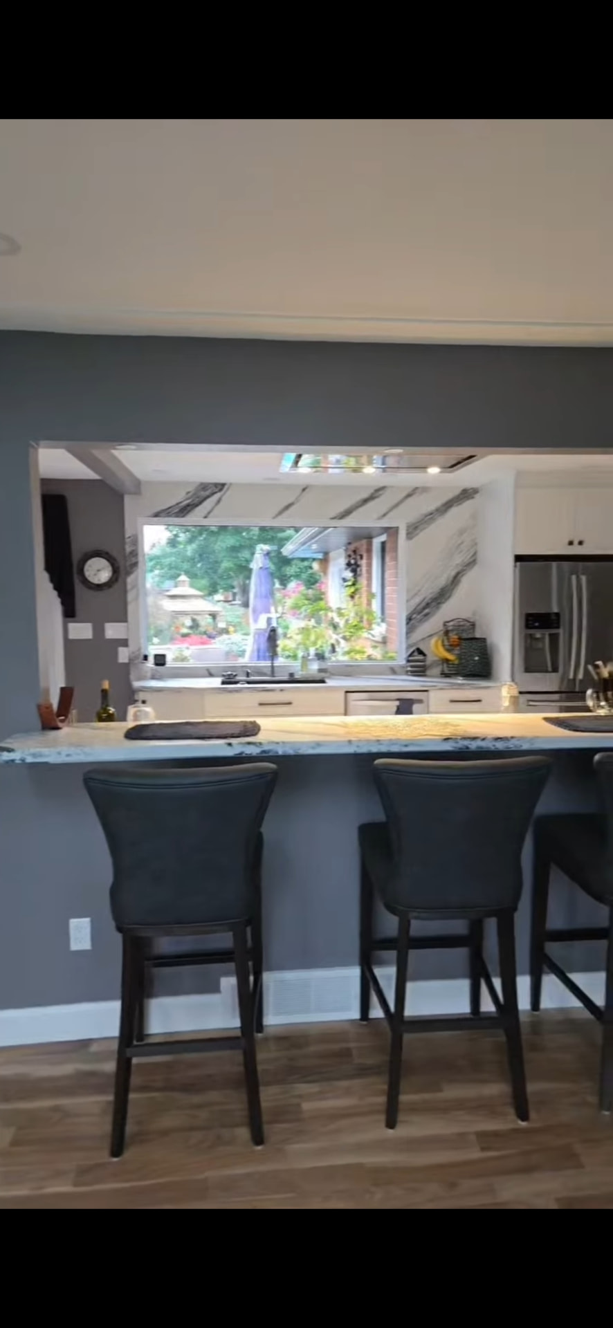 Finished breakfast bar with stone counter and stools looking through to the kitchen