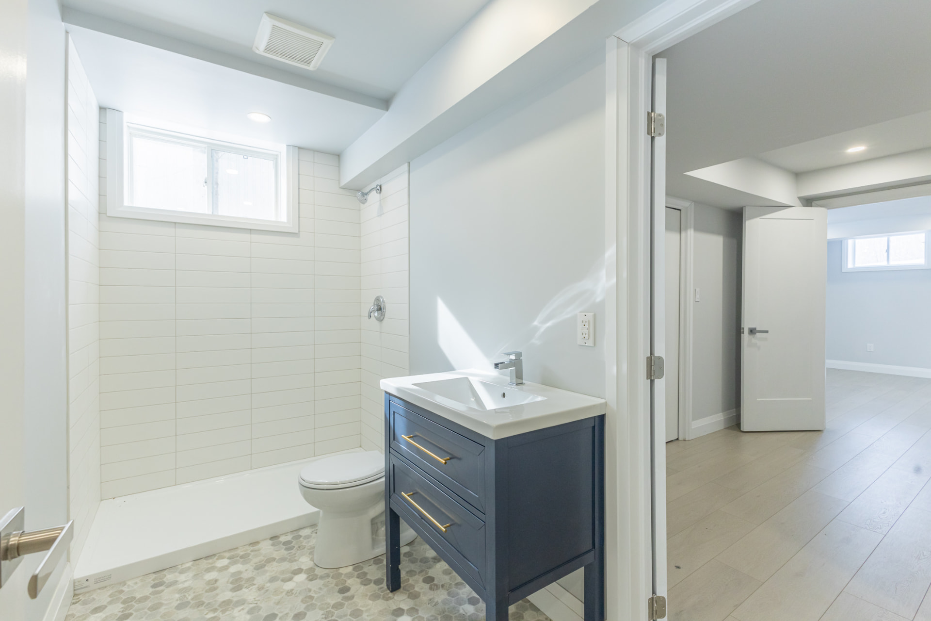 Basement bathroom with navy vanity, gold hardware and tiled walk-in shower